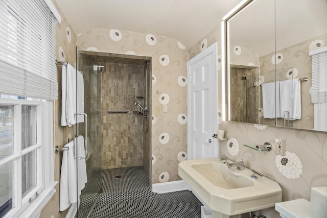 bathroom with a sink, a shower stall, and wallpapered walls