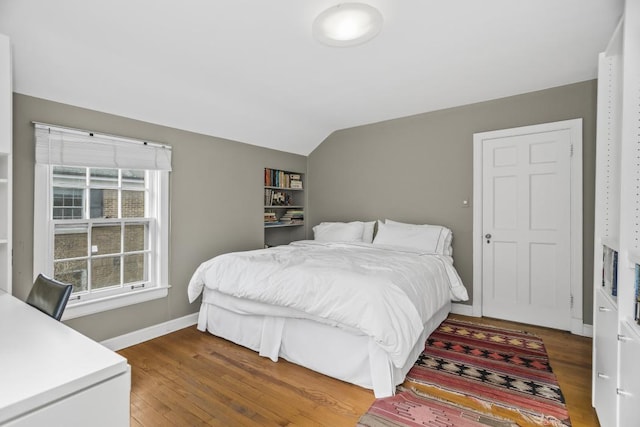 bedroom with dark wood-style floors, vaulted ceiling, and baseboards