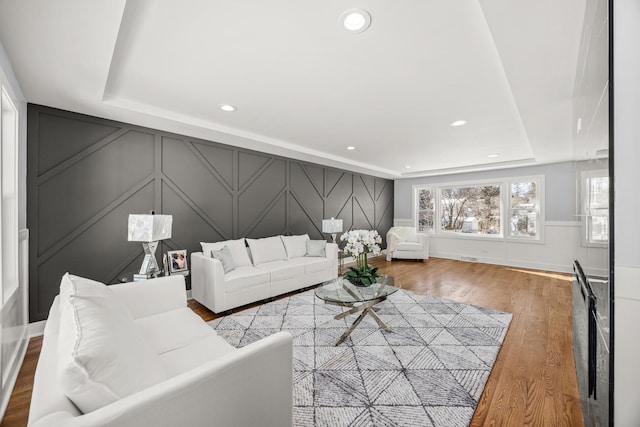 living room featuring hardwood / wood-style floors and a tray ceiling