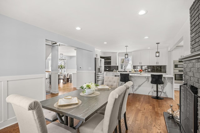 dining area with sink, a fireplace, light hardwood / wood-style floors, and a chandelier