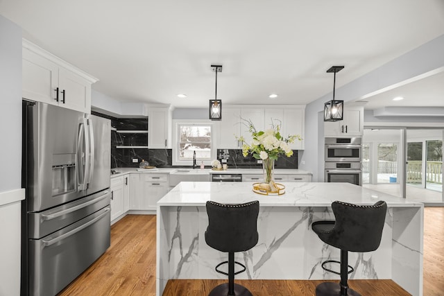 kitchen with pendant lighting, white cabinetry, appliances with stainless steel finishes, and a center island