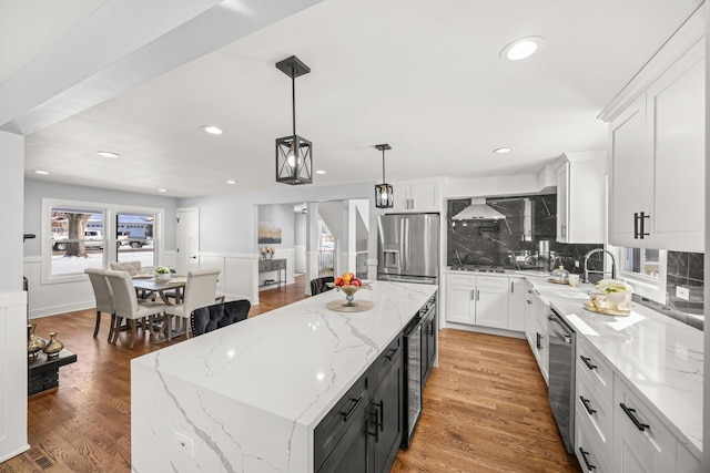 kitchen featuring hanging light fixtures, stainless steel appliances, a center island, and white cabinets