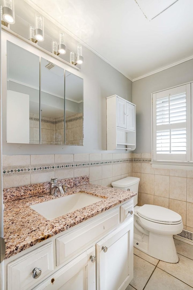 bathroom with tile patterned floors, toilet, tile walls, ornamental molding, and vanity