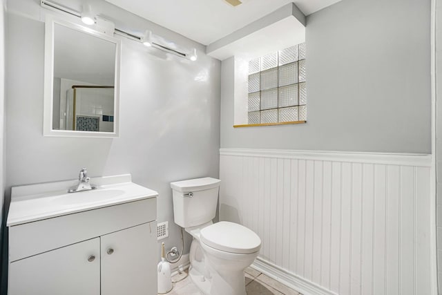 bathroom featuring vanity, a shower with shower door, and toilet