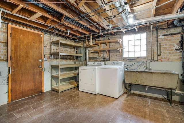 washroom with sink, independent washer and dryer, and brick wall