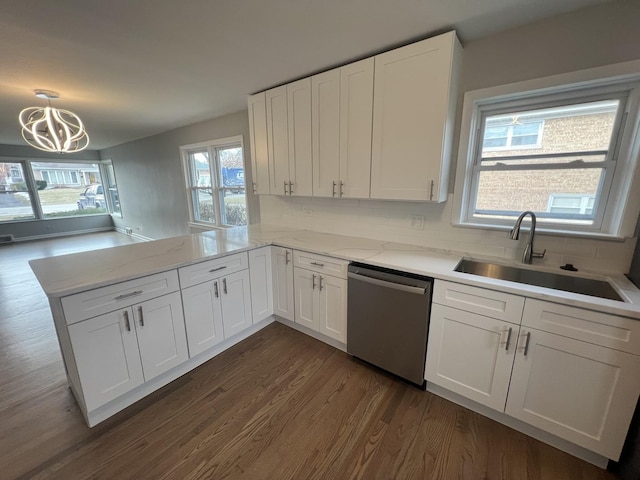 kitchen with sink, white cabinetry, stainless steel dishwasher, kitchen peninsula, and pendant lighting