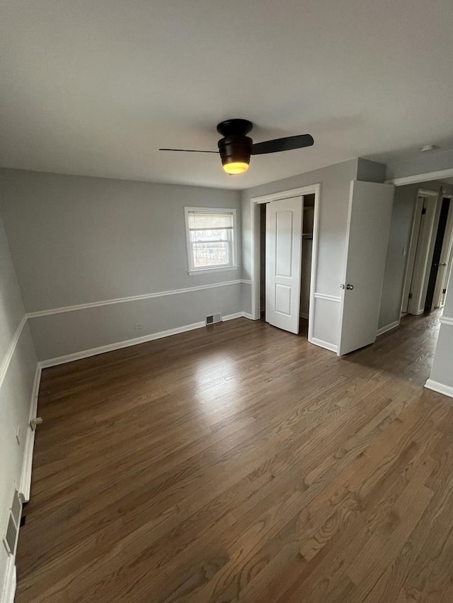 unfurnished bedroom featuring ceiling fan, dark hardwood / wood-style floors, and a closet