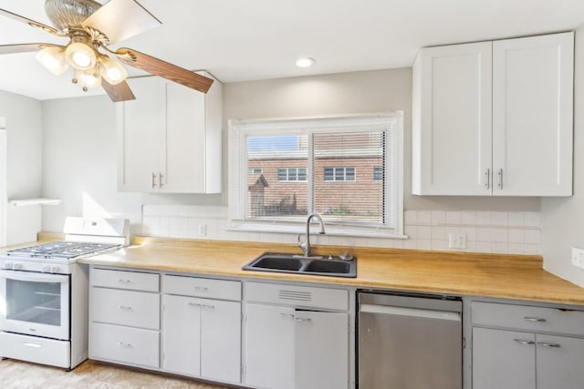 kitchen featuring white gas stove, light countertops, stainless steel dishwasher, white cabinets, and a sink