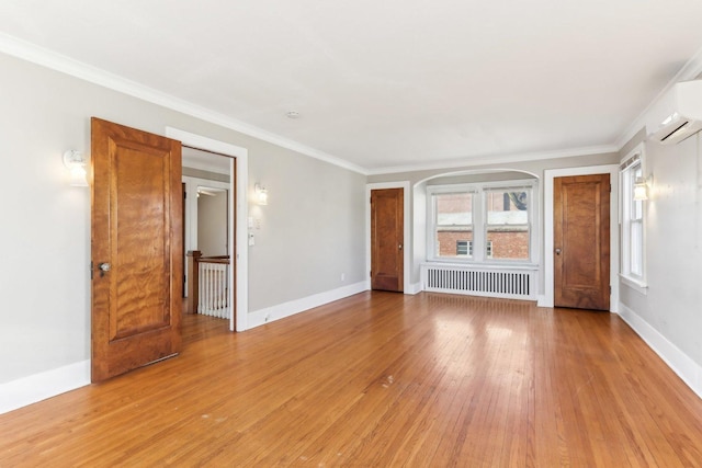 spare room featuring baseboards, an AC wall unit, light wood finished floors, and radiator