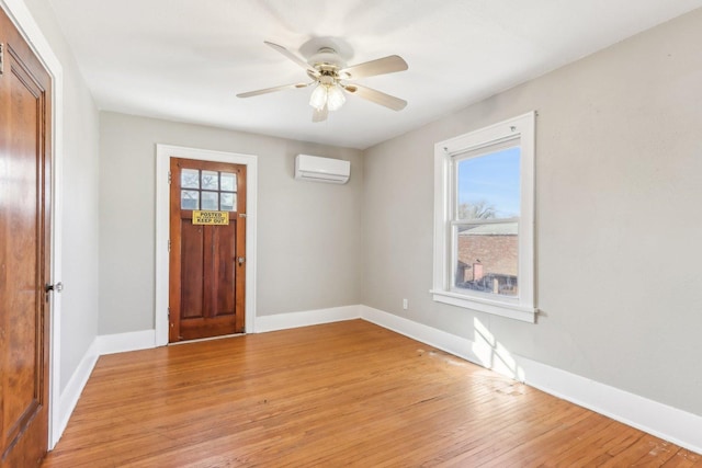 foyer with light wood finished floors, ceiling fan, baseboards, and a wall mounted AC