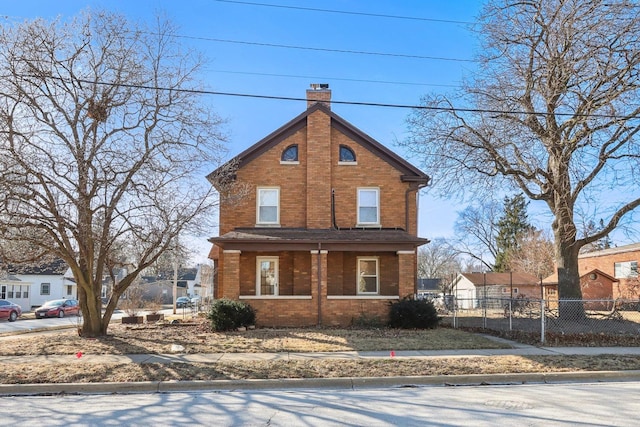 traditional-style home with a porch, brick siding, fence, and a chimney