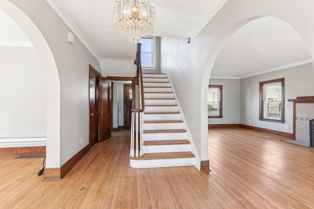 stairs featuring arched walkways, ornamental molding, wood finished floors, and baseboards