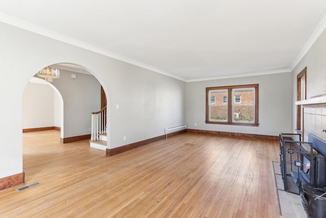 unfurnished living room with arched walkways, visible vents, baseboard heating, light wood-type flooring, and baseboards