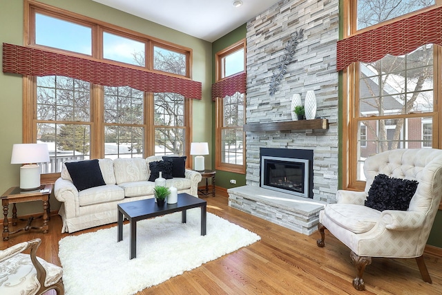 living room featuring hardwood / wood-style flooring, a towering ceiling, and a fireplace