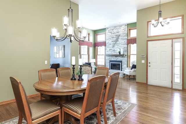 dining room featuring an inviting chandelier, hardwood / wood-style floors, and a stone fireplace