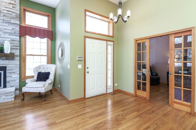 entryway featuring french doors, hardwood / wood-style floors, a towering ceiling, and an inviting chandelier