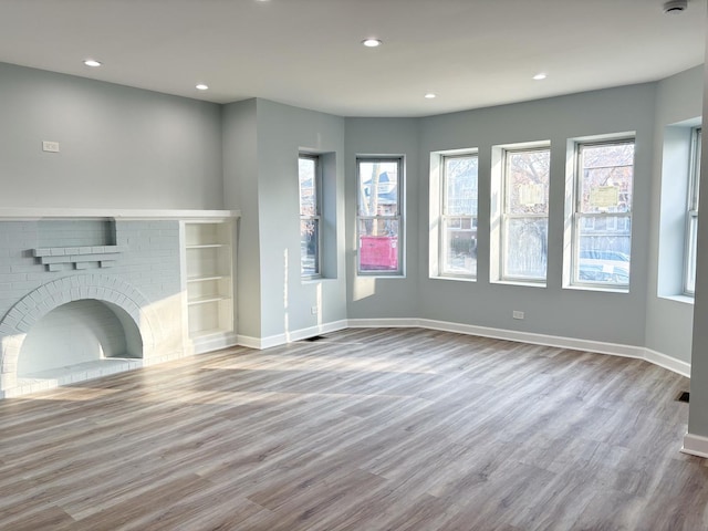 unfurnished living room featuring light wood finished floors, recessed lighting, a fireplace, and baseboards