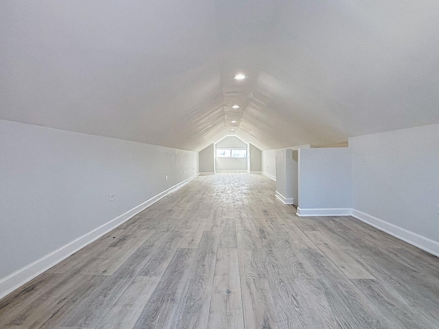 bonus room with light wood-type flooring, lofted ceiling, and baseboards