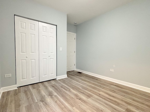 unfurnished bedroom with baseboards, a closet, visible vents, and light wood-style floors