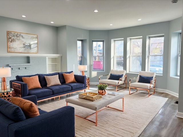 living area with a fireplace, baseboards, wood finished floors, and recessed lighting