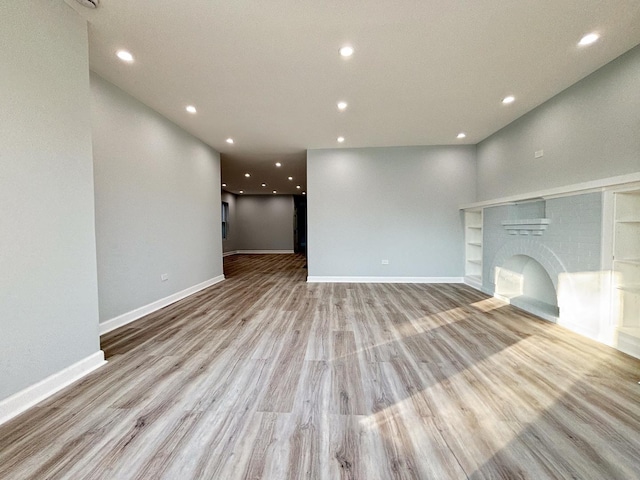 unfurnished living room featuring light wood-style floors, recessed lighting, a fireplace, and baseboards