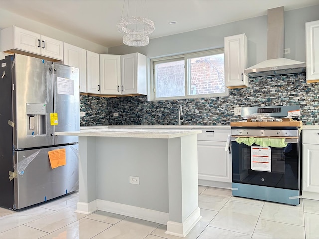 kitchen featuring pendant lighting, stainless steel appliances, light countertops, white cabinets, and wall chimney range hood