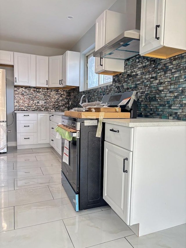 kitchen with light countertops, decorative backsplash, freestanding refrigerator, white cabinetry, and stainless steel range with electric stovetop