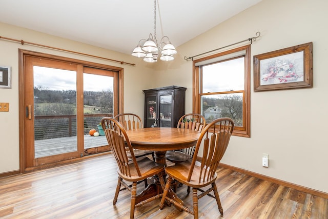 dining area with vaulted ceiling, a chandelier, and light wood-type flooring