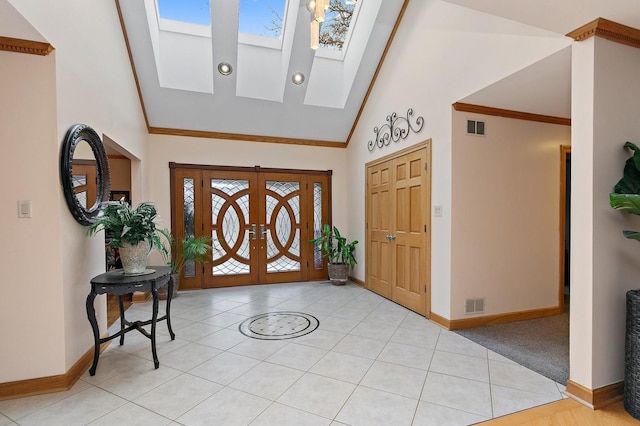 entryway featuring light tile patterned floors, crown molding, a skylight, and high vaulted ceiling