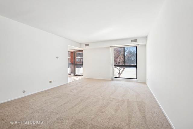 spare room featuring baseboards, visible vents, and light colored carpet