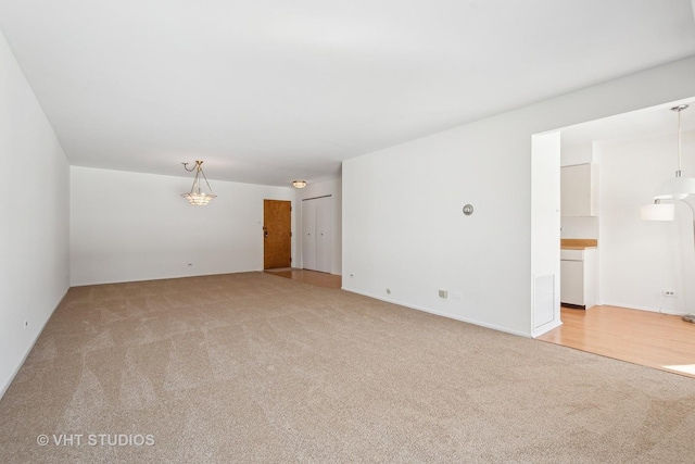 spare room featuring visible vents and light colored carpet