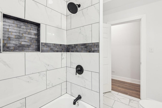 bathroom featuring toilet and tiled shower / bath combo