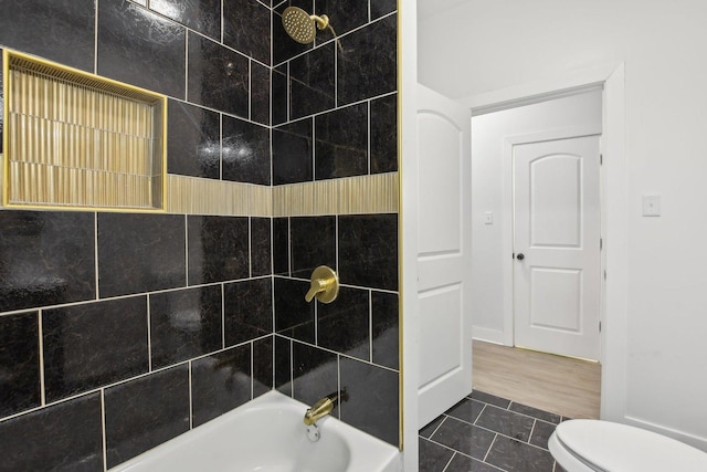 bathroom with tiled shower / bath combo, tile patterned flooring, and toilet