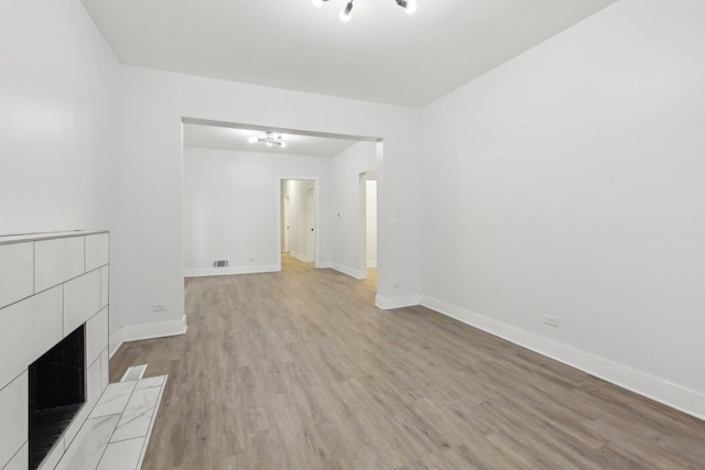 unfurnished living room featuring a tiled fireplace and light hardwood / wood-style flooring