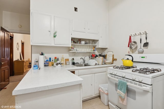 kitchen featuring white range with gas cooktop, light tile patterned floors, sink, and white cabinets