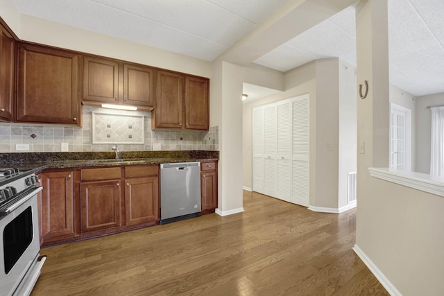 kitchen featuring stainless steel dishwasher, wood-type flooring, sink, and white stove