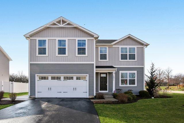 view of front of property featuring a garage, driveway, a front yard, and fence