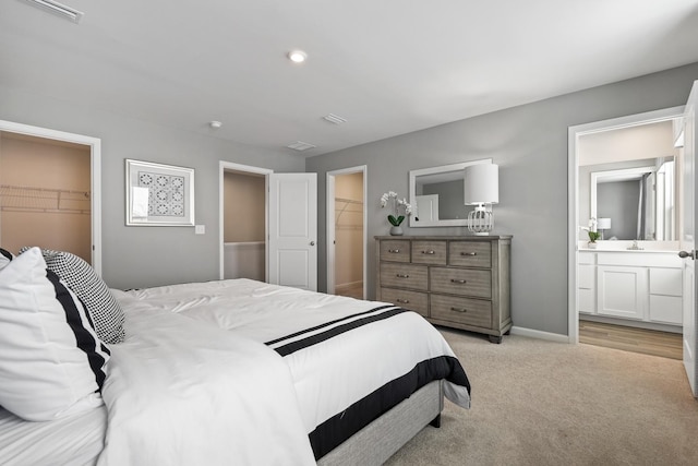 bedroom with a spacious closet, a closet, visible vents, and light colored carpet