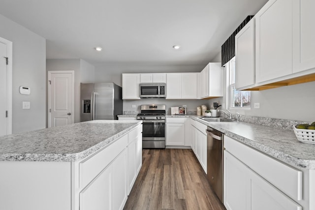 kitchen featuring dark wood-type flooring, stainless steel appliances, light countertops, white cabinetry, and a sink