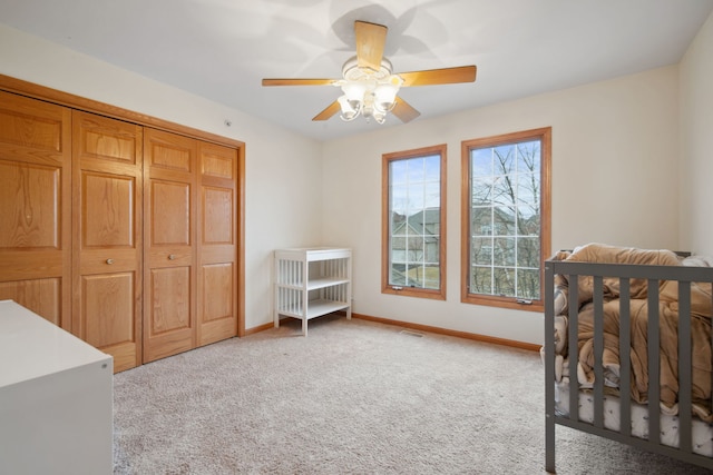 carpeted bedroom featuring a closet, visible vents, a ceiling fan, and baseboards