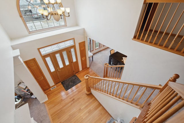 entrance foyer featuring an inviting chandelier, stairway, wood finished floors, and a towering ceiling