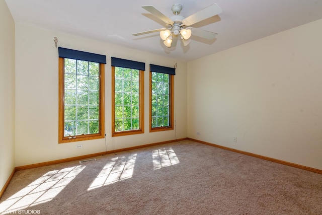 unfurnished room with carpet, visible vents, and baseboards