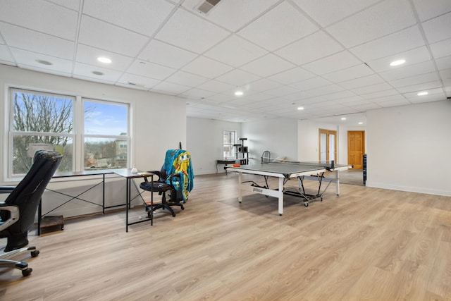 recreation room with a wealth of natural light, a drop ceiling, and light wood-style flooring