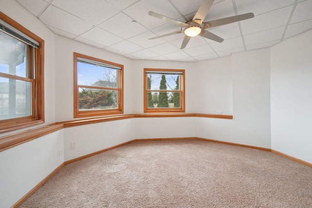 carpeted spare room featuring a ceiling fan, a paneled ceiling, and baseboards