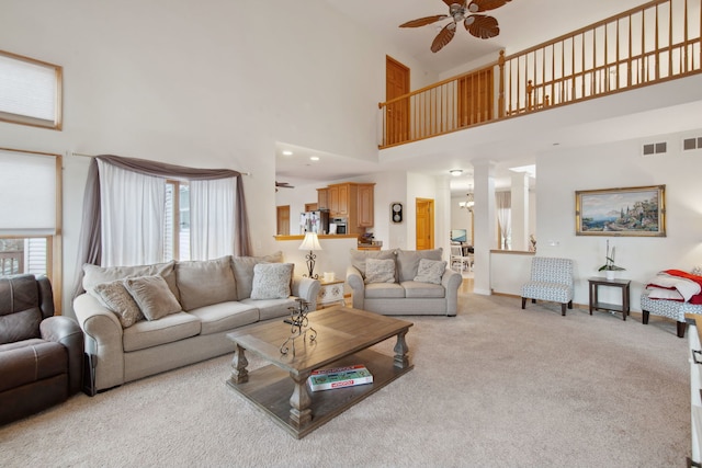 living area with visible vents, baseboards, ornate columns, light carpet, and ceiling fan with notable chandelier