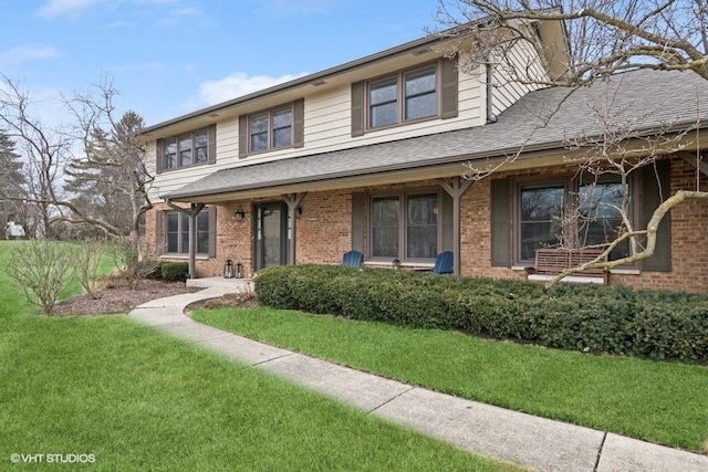 view of front of home featuring a front lawn, brick siding, and a shingled roof