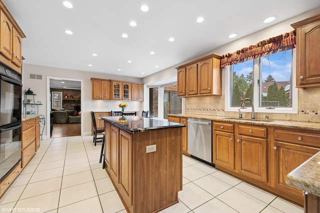 kitchen with visible vents, a sink, dark stone countertops, a center island, and dishwasher