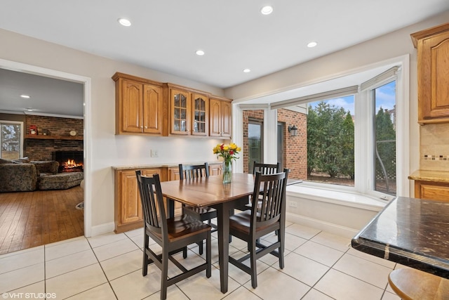 dining room featuring light tile patterned floors, recessed lighting, a brick fireplace, and baseboards