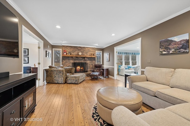 living area with baseboards, ornamental molding, a fireplace, and light wood finished floors