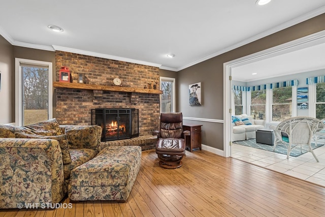 living room with a brick fireplace, baseboards, hardwood / wood-style floors, ornamental molding, and recessed lighting